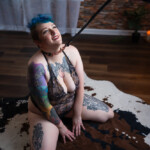 Person with short blue hair kneeling with BDSM collar at Wilmington, NC boudoir studio